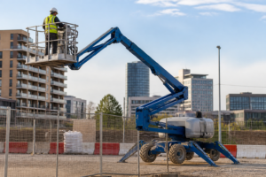 Operario con casco y arnés comprobando una plataforma articulada en una obra urbana